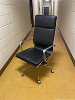 Front view of high-back black office chair showing upholstery, frame, casters