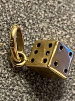 Close-up of dice charm showing pips on two faces and bail stamped PJK