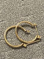 Pair of yellow gold hoop earrings on textured surface