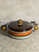Casserole pot with lid on showing wood handles and knob