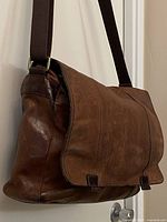 Bag hanging to show overall front view, flap closed, strap visible