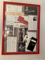 Full view of framed collage showing tickets, photos and clippings within red frame