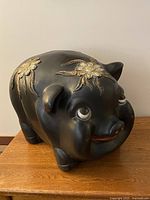 Front angled view showing piggy bank body, floral detail, stopper area hidden