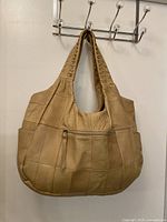Front view of tan leather patchwork hobo bag hanging on hook