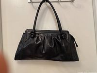 Front view of black Naturalizer leather handbag hanging, showing overall design and condition