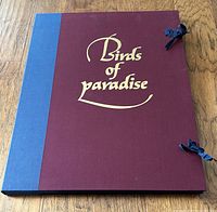 Closed portfolio showing maroon cloth boards, blue spine, gilt title, cloth ties