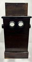 Front view showing twin eyepiece lenses and wood cabinet