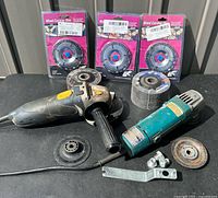 Both angle grinders, packaged discs, loose grinding wheels, toolbox top