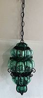 Full view of teal caged glass pendant hanging from chain