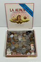 Open La Aurora cigar box filled with mixed world coins