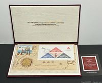 Open presentation folder showing coin, stamp sheet, interior text