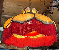 Full view of stained glass hanging lamp with red fringe suspended from ceiling