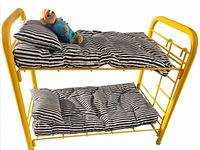full view of yellow metal bunk bed with striped bedding and plush dog