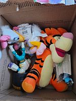 Box showing Tigger plush, Daisy Duck plush, Buzz Lightyear figure, mug, wooden sticks