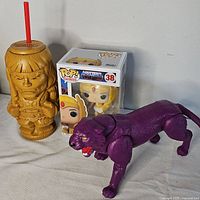 Group shot showing He-Man tiki cup, She-Ra Funko Pop box, Panthor figure