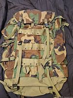 Front of woodland camouflage field pack showing flap, straps, and buckles