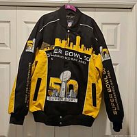 Front view of black and yellow Super Bowl 50 twill jacket showing skyline and Lombardi trophy embroidery