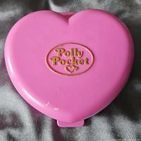 Closed pink heart compact with Polly Pocket logo visible