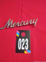 Front view of full Mercury script emblem on red background