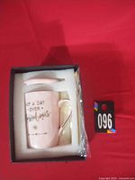 Gift set in foam showing mug, lid, spoon and lot tag