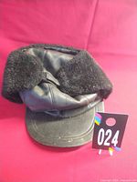 Front view of black leather ushanka hat with faux fur ear flaps and lot tag 024
