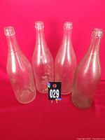 Four clear bottles standing upright on red background