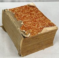 Angled view of thick volume showing marbled paper remnants and missing boards