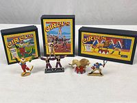 All three boxed Britains circus sets with figures displayed: clown, acrobat troupe, lion tamer and lion