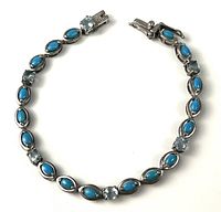 Full view of sterling silver bracelet laid flat showing turquoise cabochons and light blue stones
