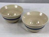 Overview of both identical cream stoneware bowls with blue stripes