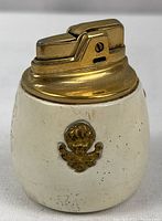 Front view of Ronson Cupid lighter showing enamel body, cherub emblem and brass mechanism