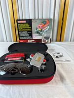 Open carrying case showing laser level, glasses, manual, outer box in background