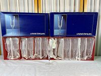 Two original blue/red Cristal d'Arques boxes and eleven flutes displayed