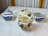Group shot of all four pieces: two lidded sugar bowls, one creamer, one open sugar bowl