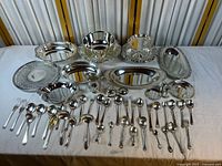 Wide shot of all silver-plated bowls, platters, trays, flatware and shakers laid out