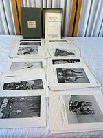 Overall view of portfolio case and multiple stacks of mounted prints spread on table