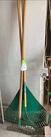 Three rakes standing upright against wall