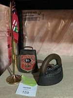 Sad iron, cowbell, flag stand with flags grouped together