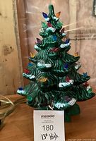 Front view of green ceramic Christmas tree with multicolor pegs and power cord visible