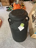 Full view of black steel milk can with lid attached