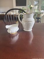 Pitcher and gravy boat side by side on table
