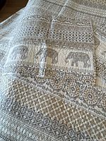 Coverlet and folded shams showing elephant and geometric pattern