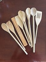 Group of nine wooden utensils laid out on table