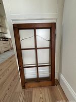 Front view of six-pane pine window frame leaning against wall