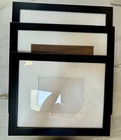 Three stacked black frames with mats