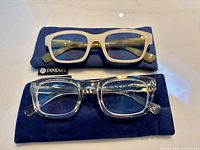 Two pairs of Peepers reading glasses on navy cases