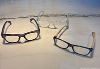 Three pairs of reading glasses laid out on surface