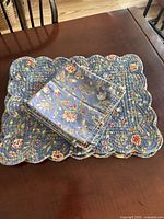 Stacked napkins on top of a placemat showing floral side