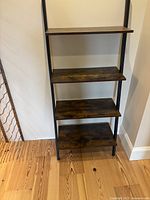 Front view showing four walnut-tone shelves and black frame