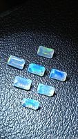 Seven rectangular faceted opals with play of color on black textured background